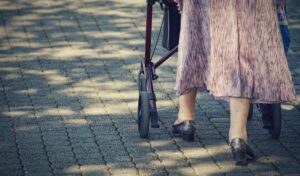 An elderly lady walking outside with a walker