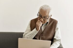 Elderly man with glasses viewing a laptop