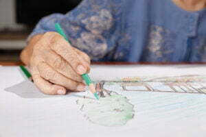 Elderly woman painting color on her drawing with daughter , hobby at home