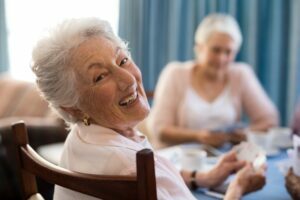 Smiling senior woman playing cards with friends