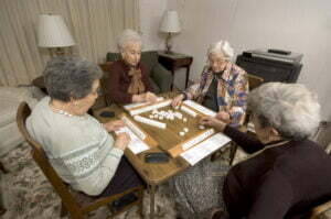 Group of happy senior women playing mah-jong with friends at Heidi's Haven Assisted Living Facility